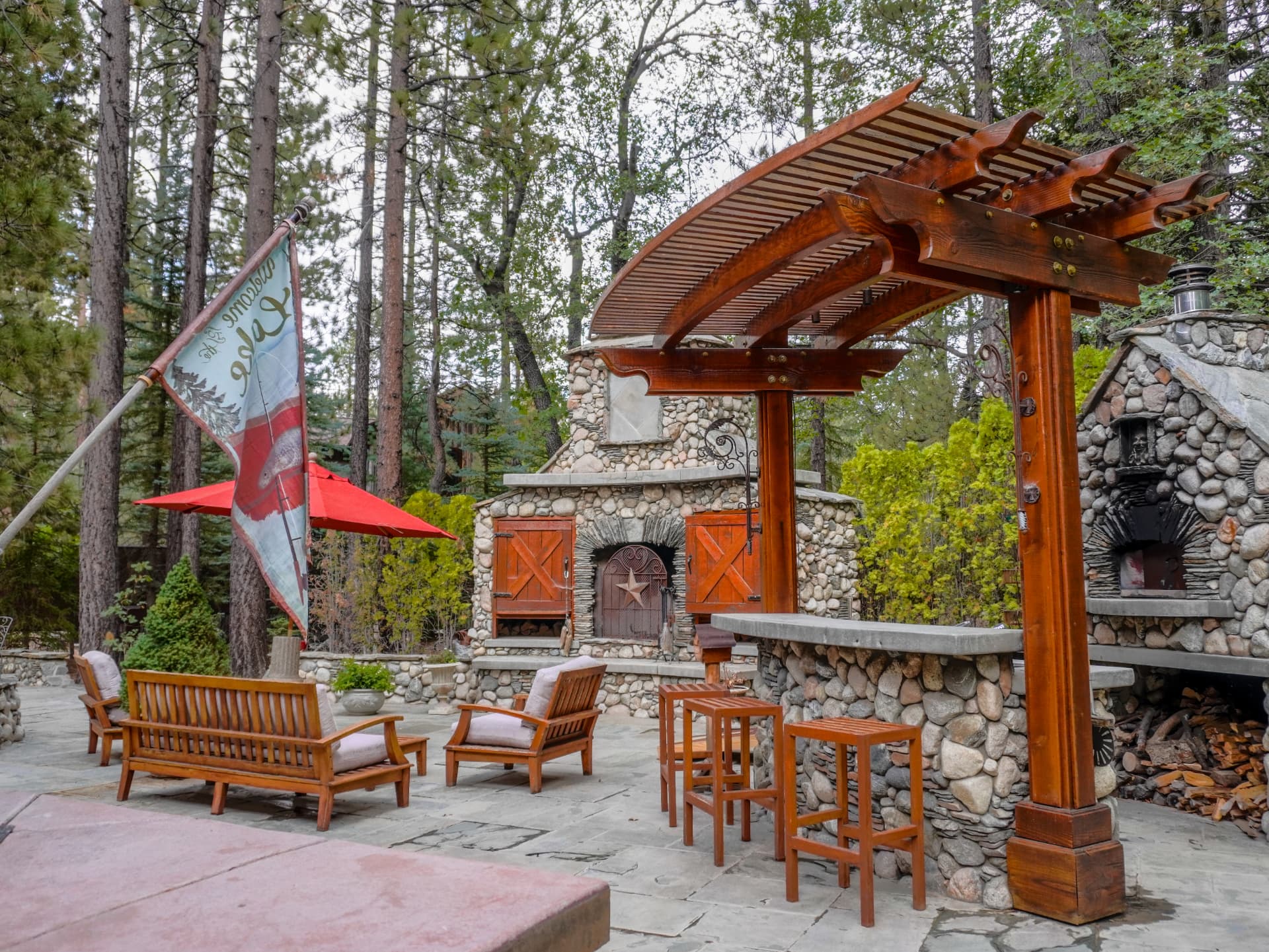 Flagstone patio with river-rock fireplace, wood-fired pizza oven and curved arbor bar