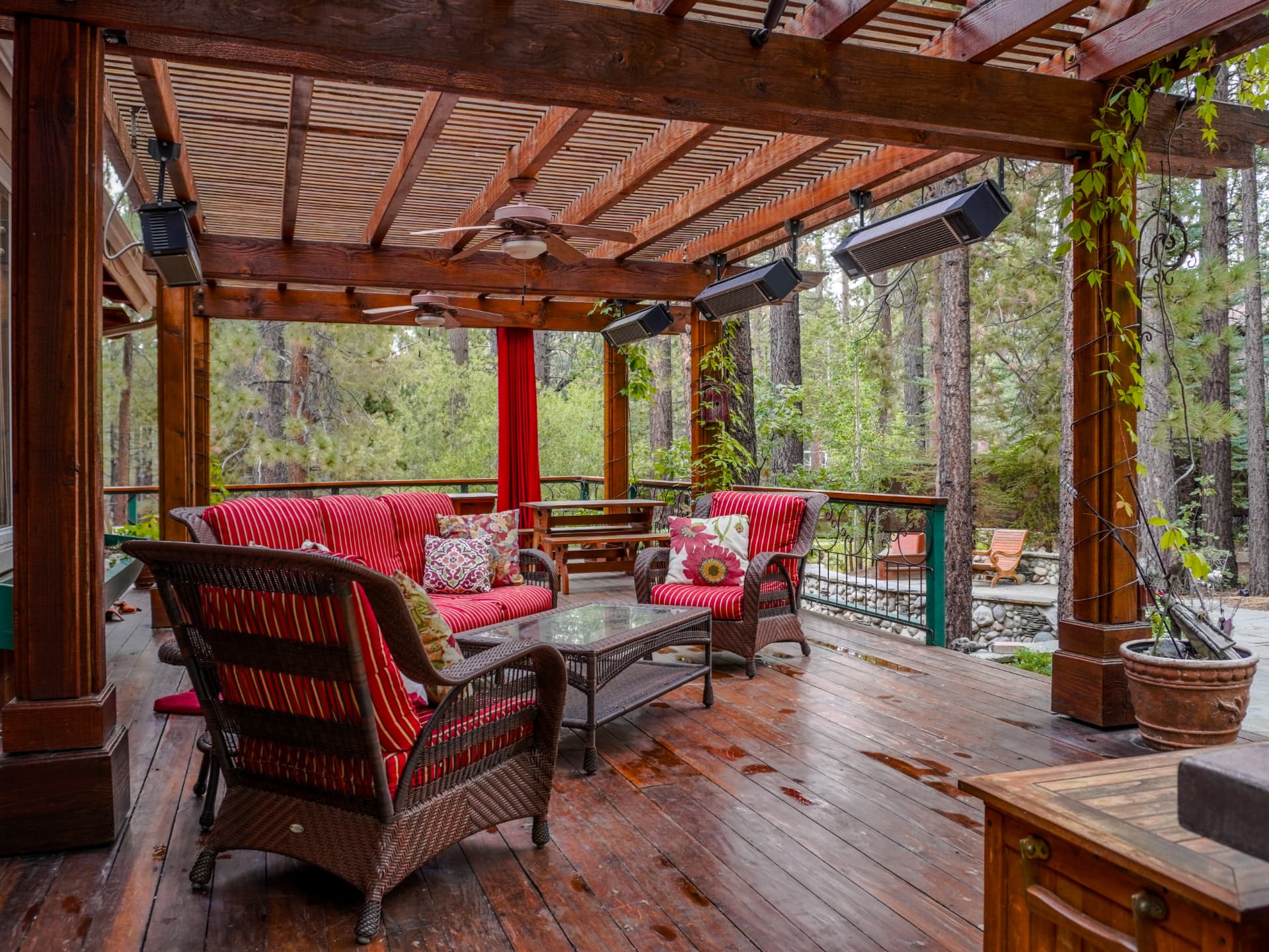 Heated outdoor lounge under the pergola with wicker seating and forest views